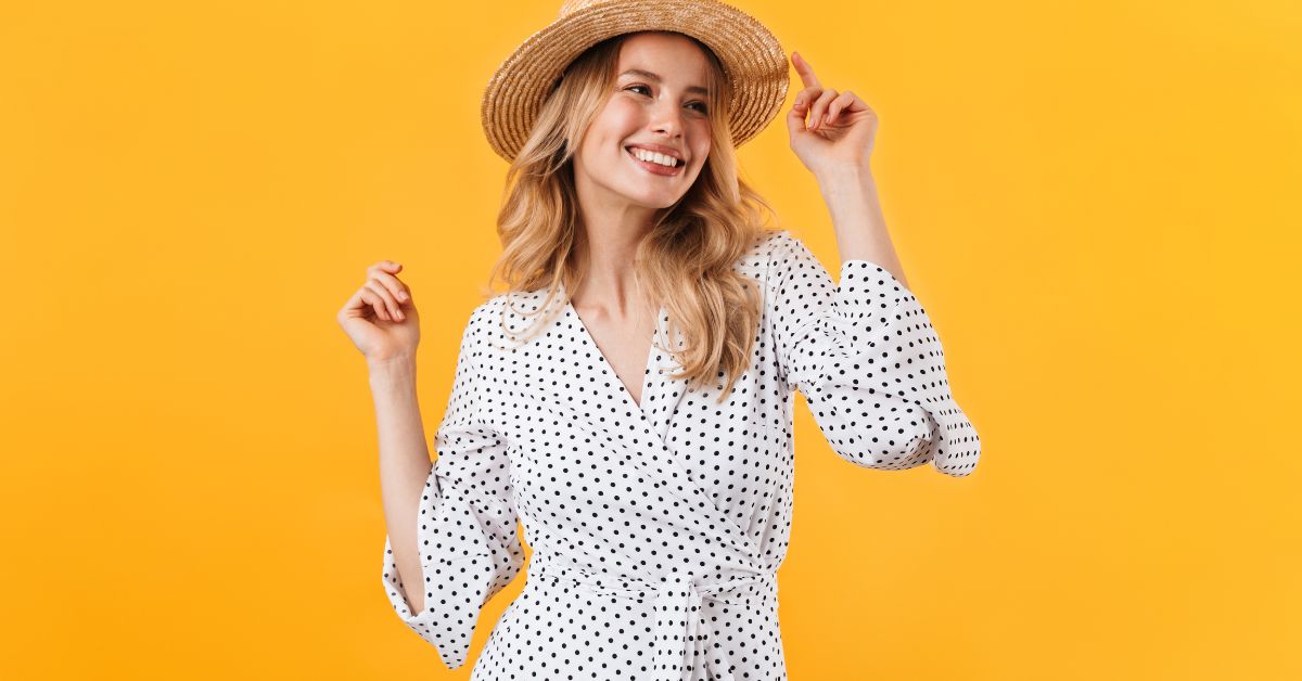 Kvinde i en hvid kjole med prikker smiler